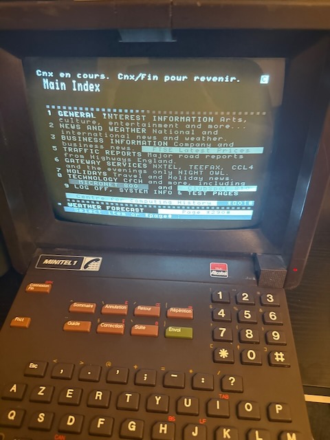 The same Minitel terminal showing the Telstar service with "General Interest", "News and Weather", "Business Information", "Traffic Reports", "Gateway Services", "Holidays", "Technology", and "Log off, system info & test pages" as options